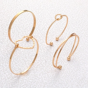 Close-up of luxury gold bracelet set featuring heart links and twisted metal details