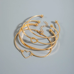 Detail view of 5-piece gold bracelet set featuring heart charms and twist designs