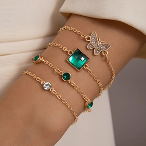 Gold layering bracelets set with emerald zircon butterfly pendant on female wrist
