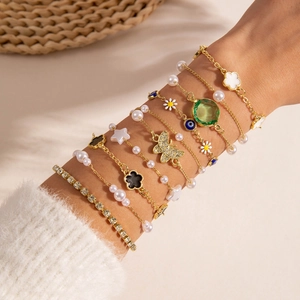 Detailaufnahme mehrlagiger goldener Boho-Armbänder mit Anhängern und Blumenakzenten