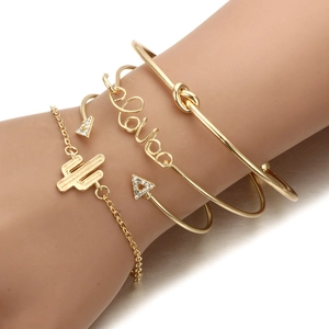 Detail von vierteiligem goldenen Armband-Set mit Love-Schriftzug und Kaktus-Anhängern