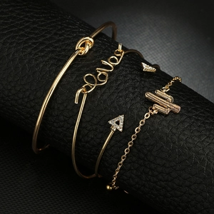 Makroansicht des goldenen Sets mit Love-Armreif, Knoten-Manschette und Sternenarmband