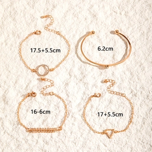 Detail von vierteiligem Goldarmband-Set mit Herz, Kreis und Dreieck auf Steinuntergrund