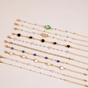 Dettaglio di nove bracciali alla moda dorati con ciondoli vari e perle artificiali