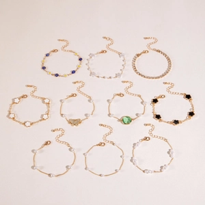Dettaglio del set di 10 bracciali dorati con cuore color smeraldo e ciondoli Evil Eye