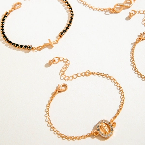 Dettaglio di diversi braccialetti placcati in oro con ciondoli e chiusure a moschettone