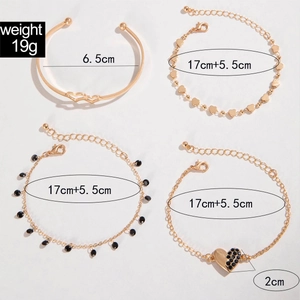 Dettaglio di un set di 4 bracciali dorati con ciondoli a cuore e pietre nere