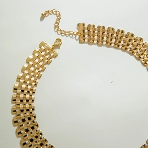 Detail of gold woven chain necklace with textured link structure and lobster clasp