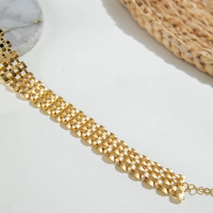 Detailed view of chunky gold chain bracelet with woven links and extension chain detail