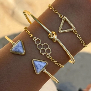 Close-up of four-piece gold bracelet set with geometric marble stone and honeycomb charms