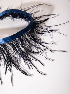 Détail macro du tour de cou gothique en plumes bleu foncé avec ruban et texture douce
