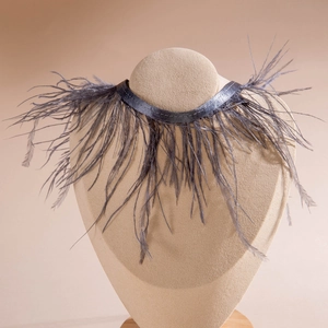 Détail de collier gothique en plumes gris foncé montrant les textures et le ruban satin