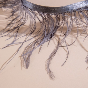 Gros plan de plumes d'autruche gris argenté cousues sur un ruban de satin pour bijoux gothiques