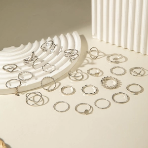 Detailset aus 23 silbernen Ringen mit Herz, Perle und Blatt auf weißem Steinboden