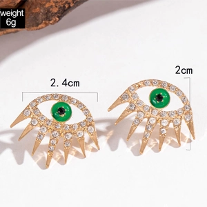 Golden eye-shaped earrings with rhinestones and green pupils on white background