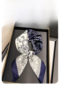 Detail of a 70cm square silk scarf featuring blue paisley patterns on a display tray