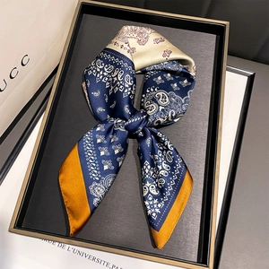 Detailed close-up of navy and cream paisley silk scarf tied in a stylish knot