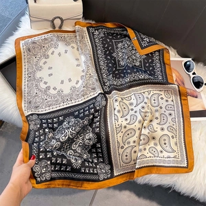Detailed view of paisley silk square scarf with elegant earth tone patterns on plush fabric
