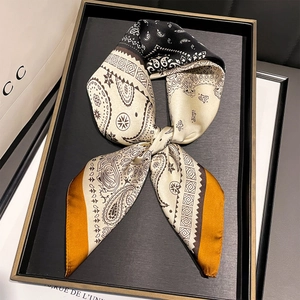 Detail of paisley print silk scarf in a bow shape on a gold-rimmed display tray