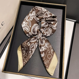 Detailed close-up of folded paisley print silk scarf in brown and gold with elegant patterns