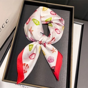 Détail d'un foulard en soie avec imprimés de coquillages et bordure rouge vif