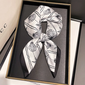 Détail d'un foulard en soie avec imprimés de coquillages sur un plateau chic