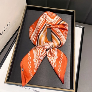 Detail of orange paisley silk scarf tied in a bow on a black display tray