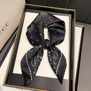 Detail of silk-like neck scarf with white paisley and geometric patterns on black