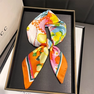 Détail d'un foulard en soie avec des imprimés vibrants d'agrumes et de motifs floraux