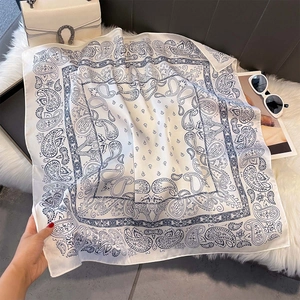 Close-up of vintage blue paisley pattern on white silk scarf with luxury accessories