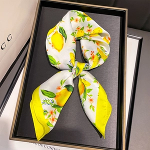 Foulard en soie tendance avec imprimé citron et bordure jaune sur plateau d'exposition