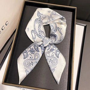 Detailed view of paisley silk scarf tied in a bow on a tray showing premium texture