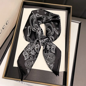 Macro detail of silk-like black neckerchief with white paisley print tied in a bow