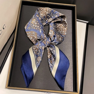 Detail view of a vintage paisley silk scarf tied in a bow on an elegant display tray