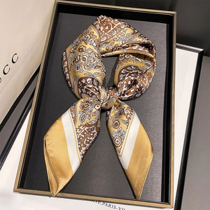 Detail of elegant paisley print silk scarf tied in a black golden trim display tray