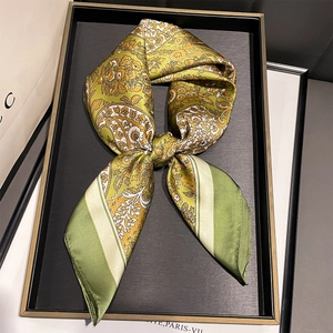 Detailed view of paisley silk scarf with rolled edges in mustard yellow and green