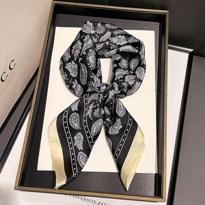 Detail of a vintage black and white paisley silk scarf tied in a bow on a luxury tray