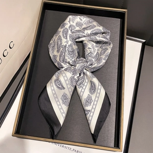 Detail of paisley print silk scarf tied in a bow on a display tray for a luxury look