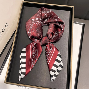 Detail of burgundy paisley silk scarf with stripes on an elegant gold rimmed tray