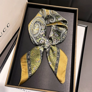 Detail view of mustard yellow paisley satin scarf folded elegantly on a black tray