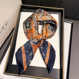 Detail of silk-like satin scarf with paisley floral print tied in a bow knot