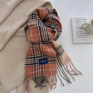 Detailopname van retro oranje geruite sjaal met kwastjes en elegant stoffen label