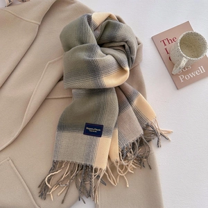 Close-up of a warm plaid knit scarf with tassel fringe details and a woven brand label