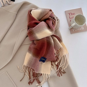 Close-up of thick plaid scarf texture with tassel edges and classic label on a coat
