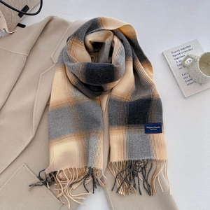 Close-up of yellow and grey plaid scarf texture with elegant fringe on wool coat