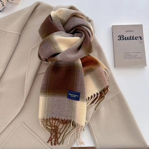 Close-up of thick plaid tassel scarf with Elegant & Classic woven label on wool coat