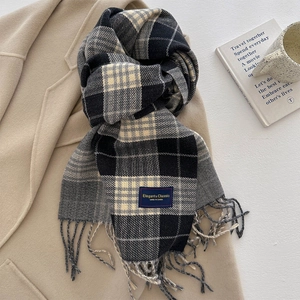 Klassieke donkere geruite sjaal met franjes op een beige jas voor de winter