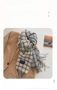 Detail of checkered plaid scarf in beige and grey with fringe and blue woven label