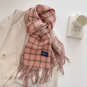 Detail of pink and brown plaid scarf with long tassels and elegant brand woven label