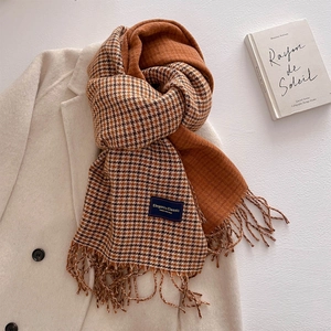 Detail of double-sided houndstooth scarf with tassels on ivory wool coat